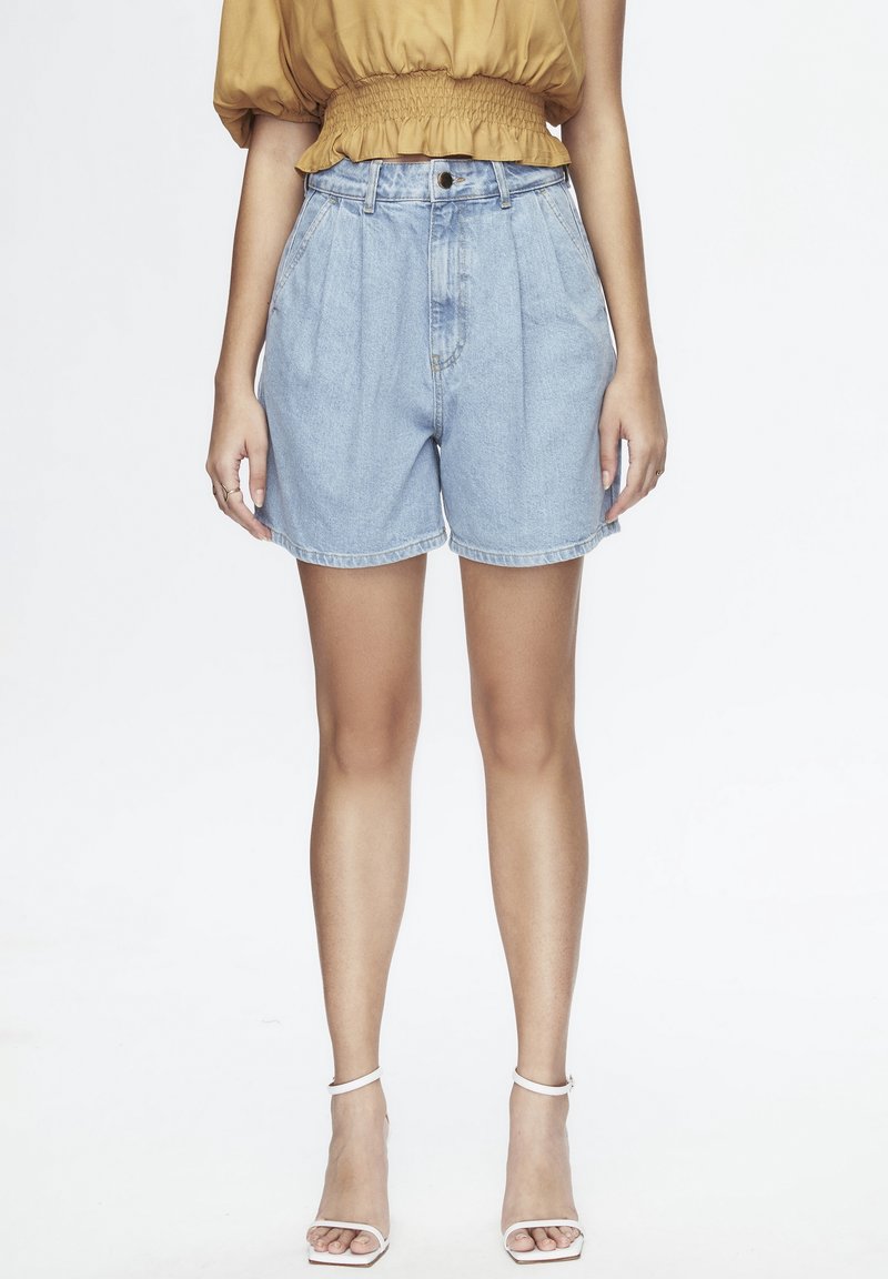 Shorts de mezclilla azul claro de tiro alto con plisados, dobladillos enrollados y cierre frontal de botones. Textura suave, diseño casual. Bolsillos frontales planos.