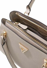 Sac à main texturé gris avec ferrures dorées, doté d'une fermeture éclair, de plusieurs compartiments et d'un détail de logo triangulaire.