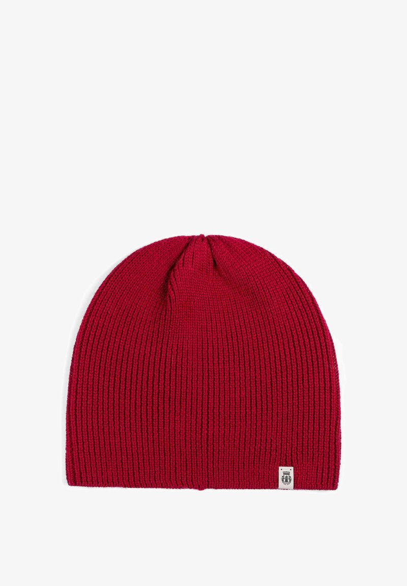 Red knitted beanie hat with a ribbed texture and a small white logo patch at the bottom right. Soft material and rounded top design.