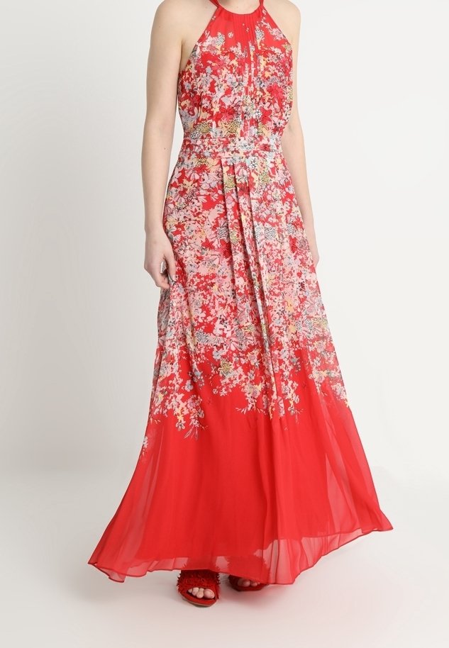 Robe longue fleurie rouge à col halter, avec une jupe fluide, un tissu léger et des motifs floraux complexes en rose et vert.