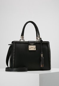 Sac à main en cuir noir avec poignée tressée, quincaillerie en argent, accents cloutés et une bandoulière amovible. Il dispose d'une fermeture à cadenas et d'un logo de marque.