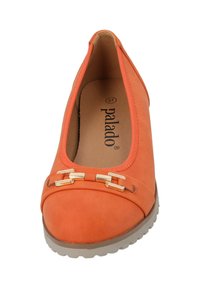 Zapato plano naranja con una textura suave, con puntera redondeada, herrajes decorativos en dorado en la parte delantera y una suela flexible gris.