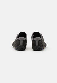 Scarpe da ginnastica nere con una suola in gomma testurizzata, dettagli grigi, un design a profilo basso e linguette posteriori per una facile calzata.