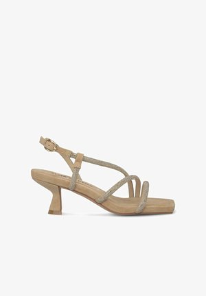 Beige high-heeled sandal with strappy design, featuring sparkling embellishments and a block heel. Suede texture enhances elegance.