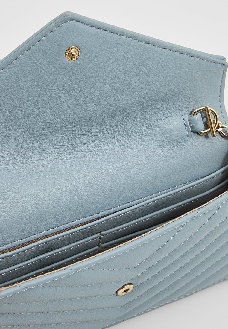 Billetera de cuero azul claro con un diseño acolchado texturizado. Cuenta con un cierre a presión en tono dorado y un anillo para llaves en el interior.