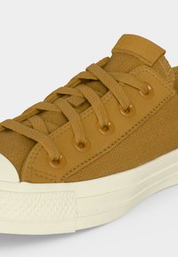 Κοντό πάνινο παπούτσι σε ταμπά χρώμα με κορδόνια ίδιου χρώματος, μεταλλικές οπές, λευκή καουτσούκ σόλα και ενισχυμένη μύτη.