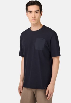 Camiseta de manga corta de color azul marino hecha de tejido suave, con un bolsillo en el pecho y un corte relajado. Cuenta con cuello redondo y detalles de costura.