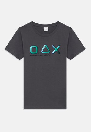 T-shirt cinza de manga curta com gola redonda. Apresenta um logo "OAX" brilhante e colorido e o texto "GAME ON" em preto ao centro. Tecido macio.