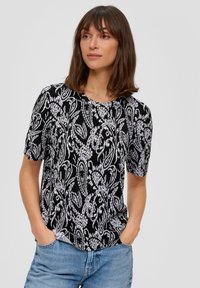 Zwart-wit gestreepte top met korte mouwen en een geribbelde textuur. Heeft een ronde halslijn en een losse pasvorm, gecombineerd met lichtblauwe jeans.
