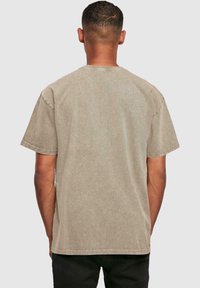 Camiseta de algodón beige con mangas cortas y cuello redondo. El diseño casual presenta un corte relajado y una textura sutil. Sin gráficos visibles.