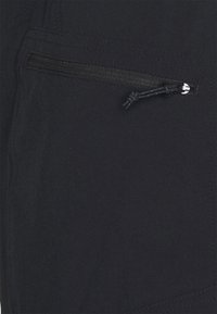 Mustakankaan, jolla on teksturoitu pinta, sisältää vetoketjullisen taskun, jossa on naru. Saumojen ompelu näkyy reunoja pitkin.