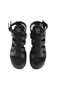 Černé sandály na tenké pásky s texturovaným koženým povrchem, s vícero širokými pásky, širokou platformou a nastavitelnou sponou na kotníku.