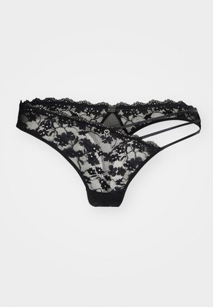 Schwarzer Spitzenstring mit Blumenmuster, ausgestattet mit gewellten Kanten und dünnen Riemchendetails. Das durchscheinende Material bietet eine zarte Textur und Optik.