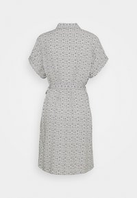 Robe ceinturée à manches courtes avec motif abstrait noir et blanc, vue de dos sur un fond clair uni.