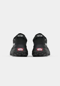 Svarte joggesko med teksturert såle, polstret krage, grå detaljer og en logo på hælen og stroppen.