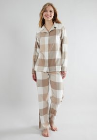 Beige and white plaid pajama set made of soft fabric; button-up shirt with long sleeves and matching loose-fitting pants.