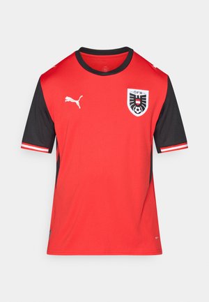 Maglietta da calcio rossa a maniche corte con maniche nere, presenta il logo Puma e lo stemma della squadra sul davanti, accenti bianchi a contrasto su colletto e maniche.