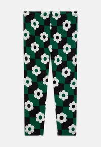 Leggings negros y verdes con un patrón de tablero de ajedrez, adornados con flores blancas y centros negros, fabricados con una tela suave y elástica.