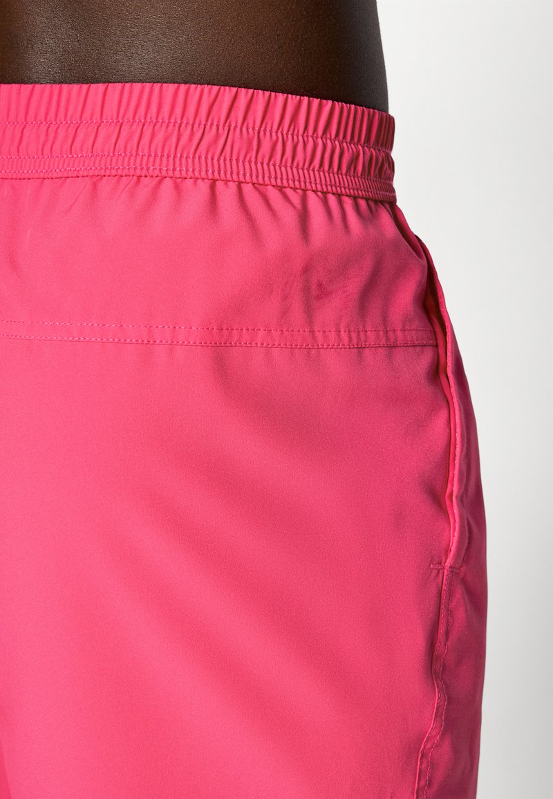 Rosa sportsshorts med elastisk talje, glat tekstur og side lomme. Har ensfarvet design og pæne syninger.