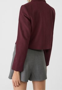 Bordeaux cropped jack met lange mouwen, van stevige stof en met een getailleerde pasvorm. Gecombineerd met grijs gestreepte shorts. Achteraanzicht weergegeven.