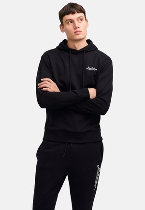 Black hoodie with adjustable drawstring, front pocket, and logo on the chest. Paired with black sweatpants featuring logo detail on the side.