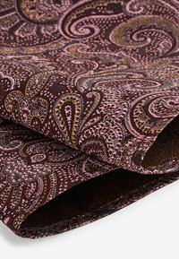 Burgundin kangas, jossa on monimutkaisia roosa- ja kultasävyisiä paisley-kuvioita, ja joka sisältää teksturoidun pinnan sekä rullatut reunat.