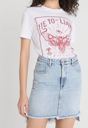 Hvid bomulds-T-shirt med rød grafisk tryk med et øje- og sommerfugledesign, kombineret med en lyseblå denim-nederdel med frynset kant.