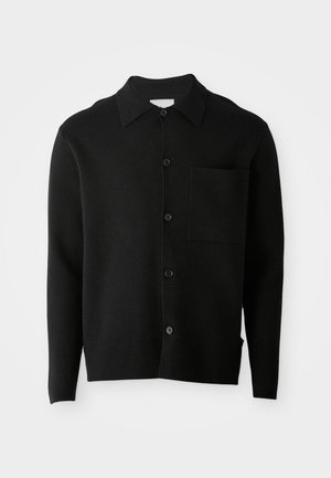 Svart långärmad knapp-up cardigan med krage och en enda bröstficka, visad mot en enfärgad ljus bakgrund.