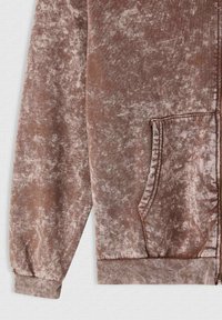 Hoodie in velluto con zip di un marrone tenue e finitura morbida e testurizzata. Presenta una tasca anteriore e polsini e orlo a costine.