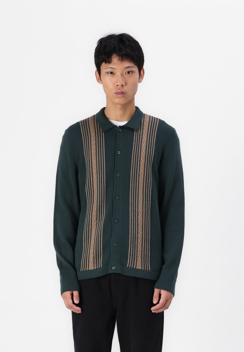 Cardigan verde con un motivo a righe verticali beige, caratterizzato da un colletto, bottoni frontali e polsini a costine.