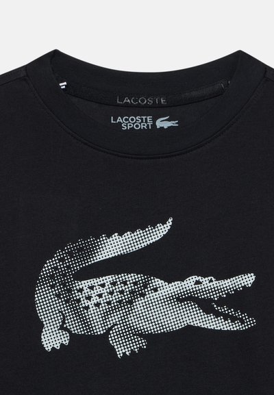 Черен спортен риза Lacoste с голям бял космат крокодилски лого, центриран отпред под деколтето.