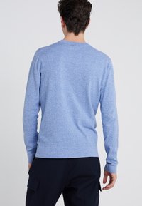 Jasnoniebieski sweter z długim rękawem o teksturowanym wzorze dzianiny, okrągłym dekoltem i ściągaczami przy mankietach. Wykonany z miękkiego, elastycznego materiału.