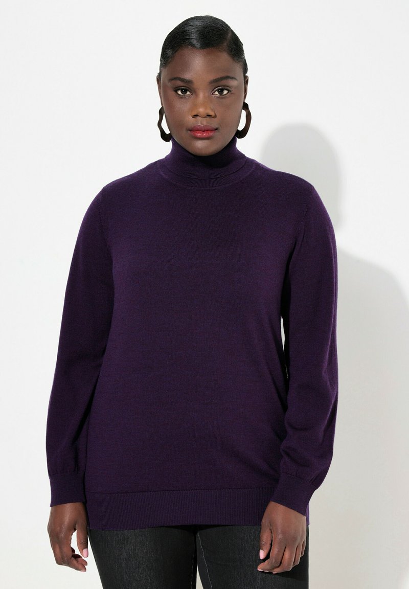 Lila Rollkragenpullover aus weichem Strick, mit langen Ärmeln und ribbeligem Saum. Getragen über dunklen Jeans, vor einem schlichten weißen Hintergrund.