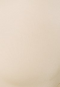 Beige naadloze bh gemaakt van gladde stof, met een lichte glans. Het ontwerp bevat subtiele textuur en geen zichtbare hardware.