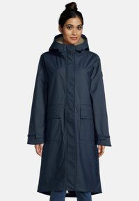 Marineblauwe waterdichte jas met capuchon, twee voorkruiden en een fleece-voering in de kraag. Heeft een rechte snit en klittenbandsluitingen bij de polsen.