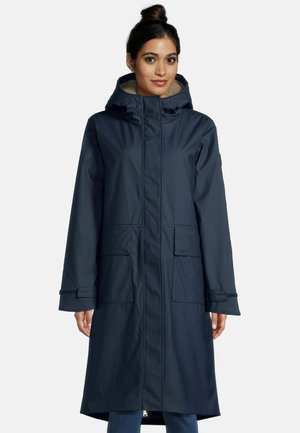 Marineblauwe waterdichte jas met capuchon, twee voorkruiden en een fleece-voering in de kraag. Heeft een rechte snit en klittenbandsluitingen bij de polsen.