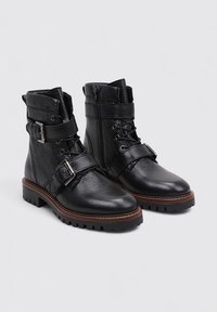 Bottines en cuir noir avec une accentuation de boucle et de sangle, finition texturée, devant à lacets, fermeture éclair sur le côté et semelle robuste.