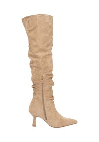 Botte beige cuissarde en daim avec un design froncé. Bout pointu et talon bloc de hauteur moyenne. Dotée d'une fermeture éclair latérale.