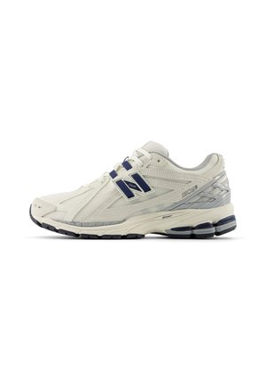 Chaussure de running New Balance blanche et grise avec des touches bleu marine, tissu mesh, semelle amortie et fermeture à lacets, vue de profil.