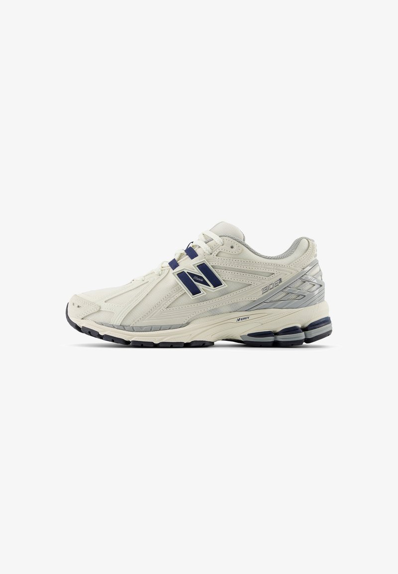 Chaussure de running New Balance blanche et grise avec des touches bleu marine, tissu mesh, semelle amortie et fermeture à lacets, vue de profil.