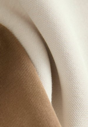 Beige és világosbarna színű pamutszövet, sima textúrával, enyhe bordázottsággal. A színek átfedik egymást, finom árnyalatváltozásokat mutatva.