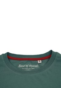 Kortärmad teal bomullströja med röd ribbad halsringning. Har logotypen "Band of Rascals" på inneretiketten. Slät textur, avslappnad design.