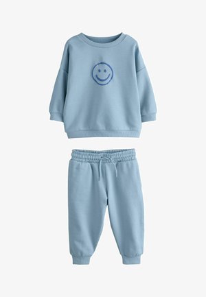 Hellblaues Sweatshirt und passende Jogginghosen aus weichem Stoff. Das Sweatshirt verfügt über ein Smiley-Grafik in der Mitte; elastischer Bund an den Hosen.