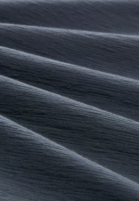 Tissu en tissu gris foncé présentant une surface texturée avec de subtiles lignes horizontales et des ondulations douces, créant profondeur et dimension.