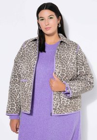 Kabát s leopardím vzorem v šedé a béžové barvě s fialovými akcenty. Měkká tkanina, volný střih, má límečkový design a boční kapsy.
