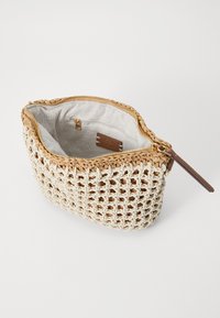 Woven beige bag with a textured design and tan accents; zippered top reveals a light-colored fabric lining and an interior pocket.