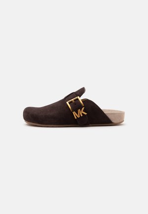Dark brown suede slip-on clog with beige sole and gold buckle detail featuring "MK" initials on the side strap.
