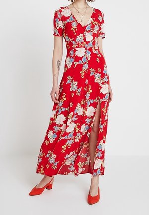 Robe longue rouge à fleurs avec manches courtes, col en V, fente latérale et jupe évasée. Présente un motif varié de fleurs colorées.
