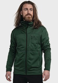 Grüne Zip-Jacke aus strukturiertem Material, mit hohem Kragen, zwei mit Reißverschluss versehenen Taschen und kontrastierenden schwarzen Akzenten.