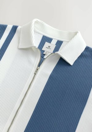 Ribbed zip-up jacket with alternating white and blue stripes. Features a white collar and silver zipper on a textured fabric.